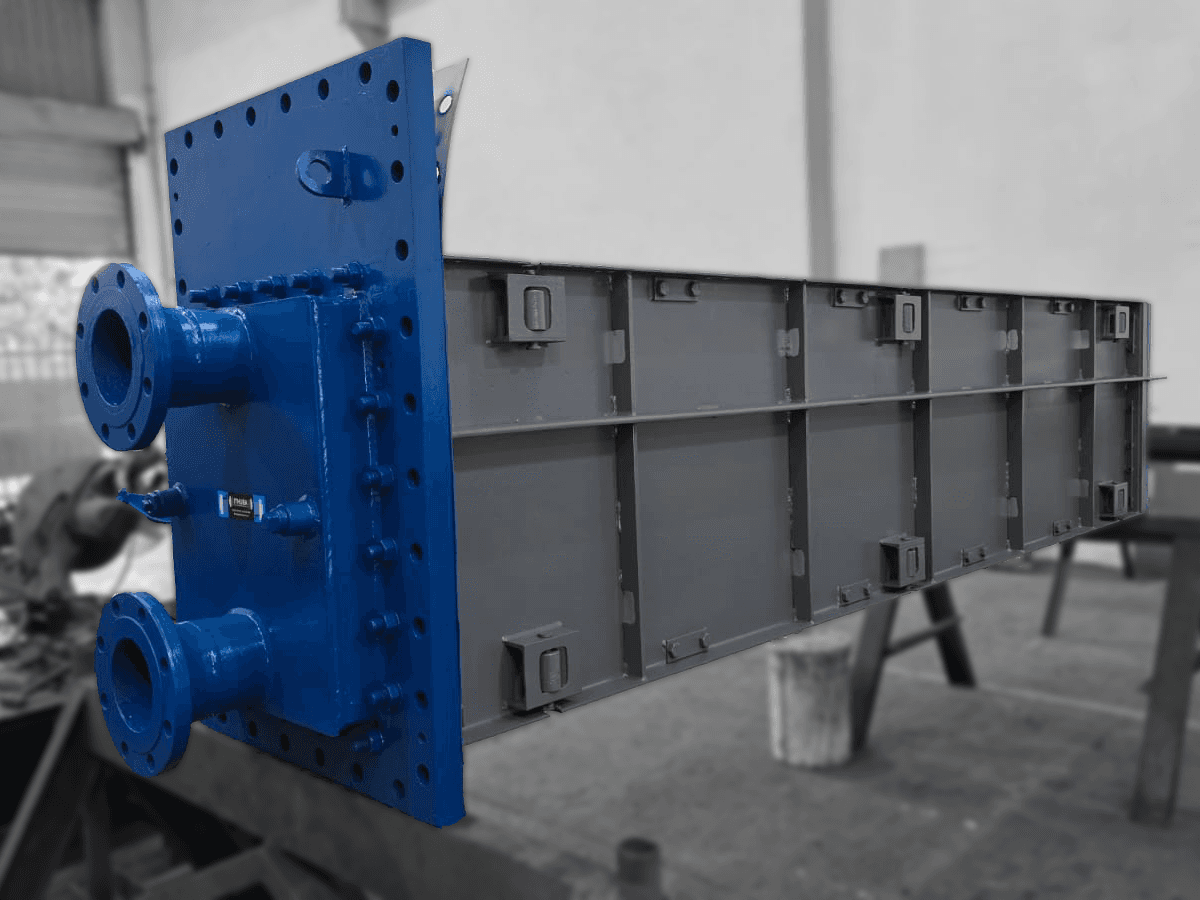 A large industrial heat exchanger with a blue flange on one end, featuring multiple bolted pipes, set against a blurred workshop background.