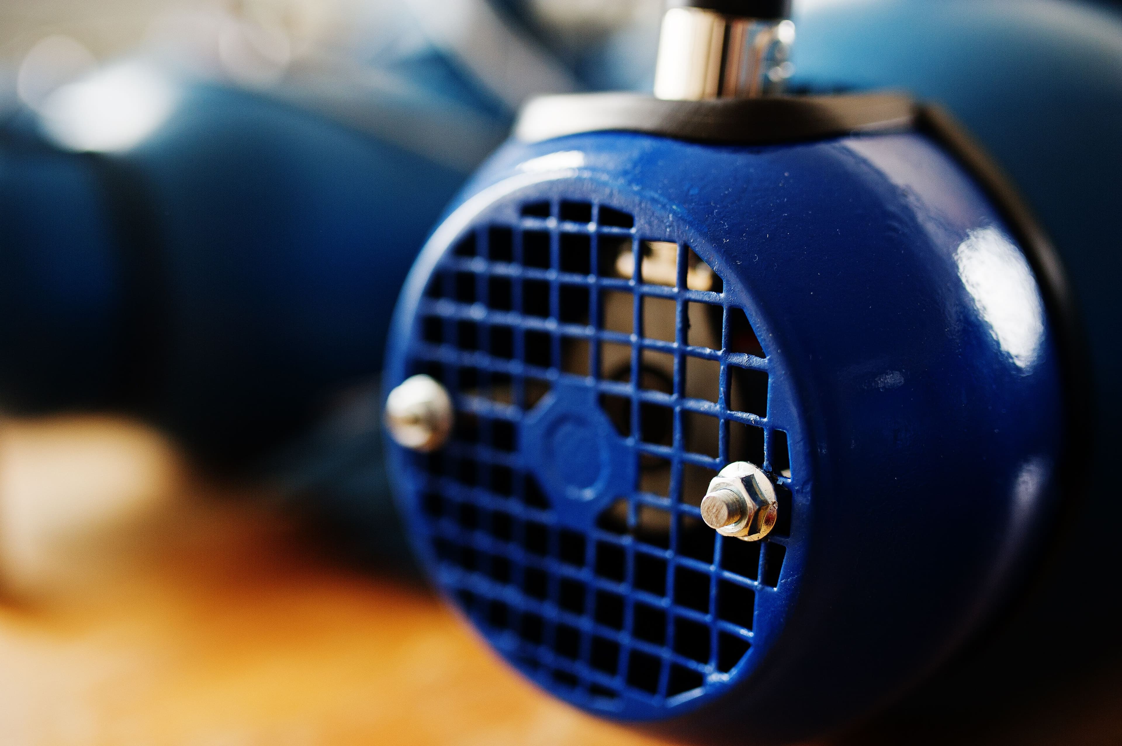 A close-up of a blue mono pump with a gridded cover and bolts on a blurred background. The tone is industrial and focused.